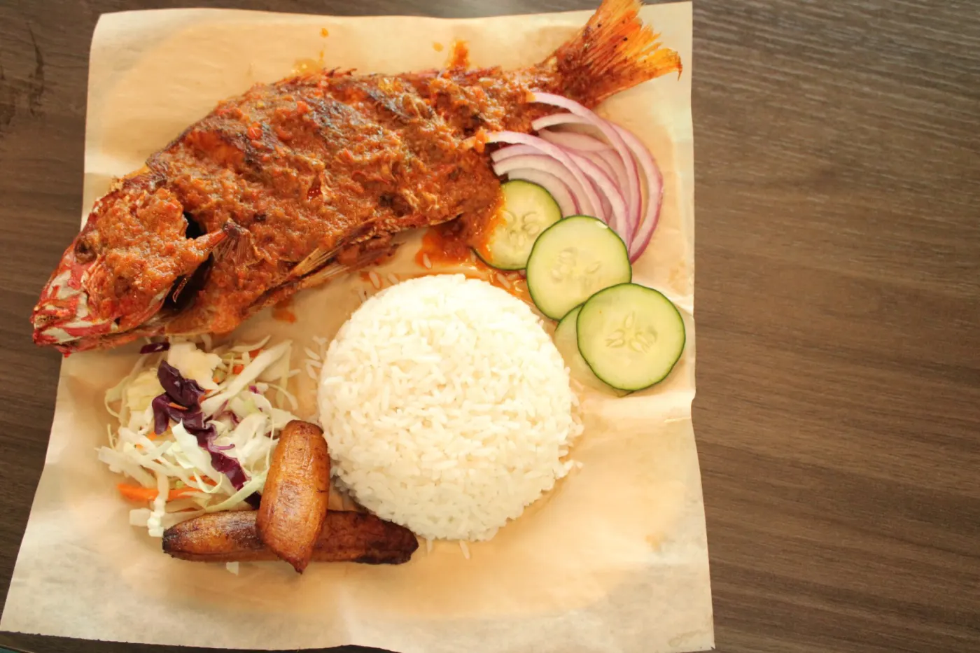 Whole fish served with white rice, cucumber, onion, and plantain